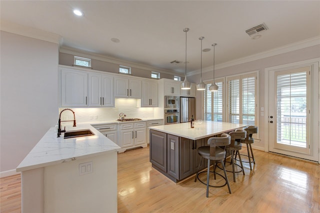 3331 Bingham Manor Ln, Houston, TX 77056 - kitchen featuring stainless steel appliances, a sink, white cabinets, ornamental molding, and a kitchen breakfast bar