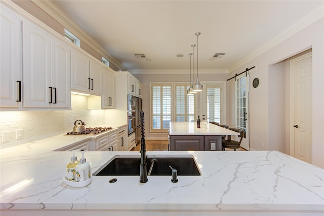 3331 Bingham Manor Ln, Houston, TX 77056 - kitchen with stainless steel appliances, a sink, a center island, light stone countertops, and decorative light fixtures
