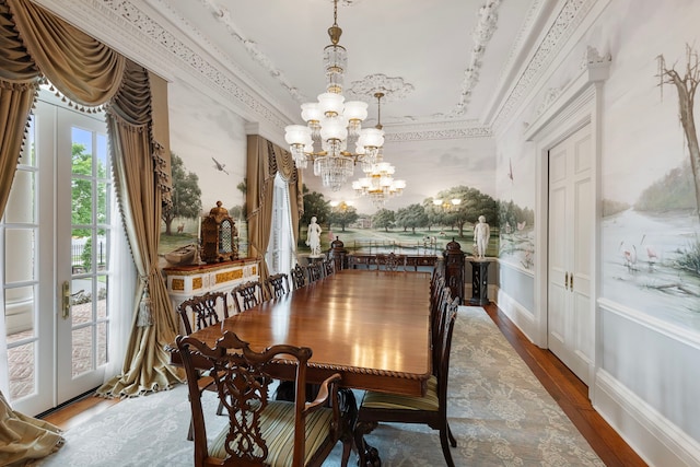 dining space with a chandelier, ornamental molding, wood finished floors, and a wainscoted wall