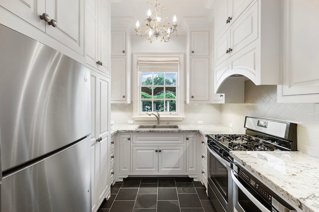 kitchen featuring stainless steel appliances, a sink, white cabinets, a chandelier, and dark tile patterned flooring