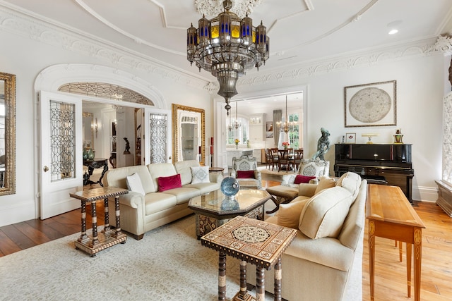 living area featuring a chandelier, hardwood / wood-style floors, ornamental molding, and baseboards