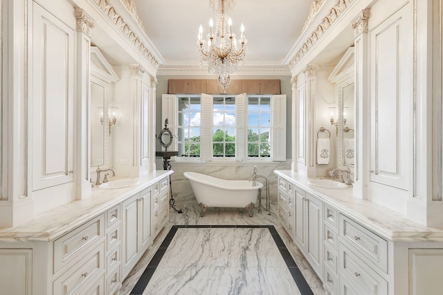 full bath featuring marble tiled floors, two vanities, a chandelier, a freestanding bath, and crown molding