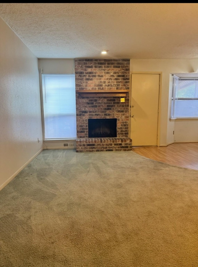 13424 Castilian Dr Unit 113, Houston, TX 77015 - unfurnished living room with carpet flooring, a fireplace, baseboards, and a textured ceiling
