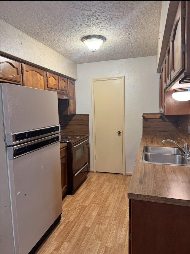 13424 Castilian Dr Unit 113, Houston, TX 77015 - kitchen with freestanding refrigerator, black electric range, a sink, light wood finished floors, and a textured ceiling