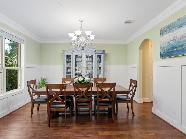 4635 Beech St, Bellaire, TX 77401 - dining space featuring arched walkways, a chandelier, ornamental molding, dark wood finished floors, and wainscoting