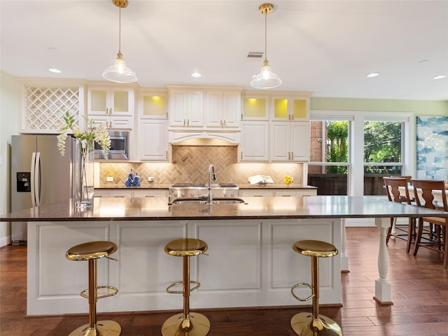 4635 Beech St, Bellaire, TX 77401 - kitchen featuring appliances with stainless steel finishes, a sink, backsplash, a center island with sink, and dark wood finished floors
