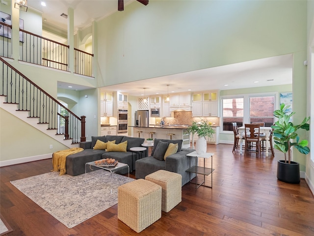 4635 Beech St, Bellaire, TX 77401 - living room with a high ceiling, dark wood-style flooring, stairway, baseboards, and arched walkways
