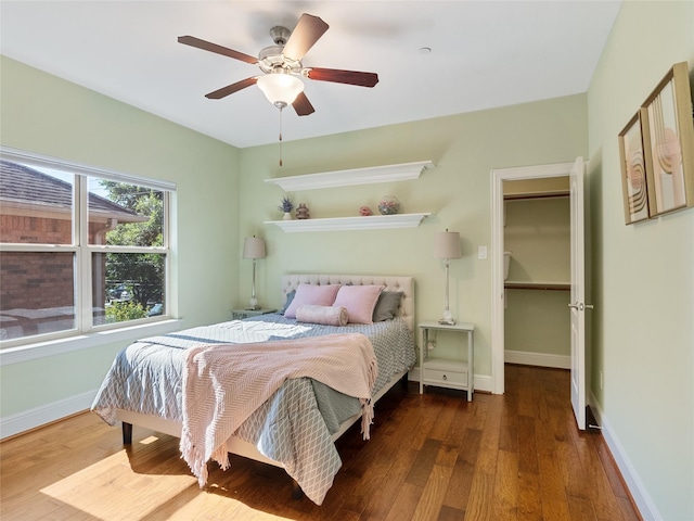 4635 Beech St, Bellaire, TX 77401 - bedroom with wood finished floors, a walk in closet, baseboards, and a ceiling fan