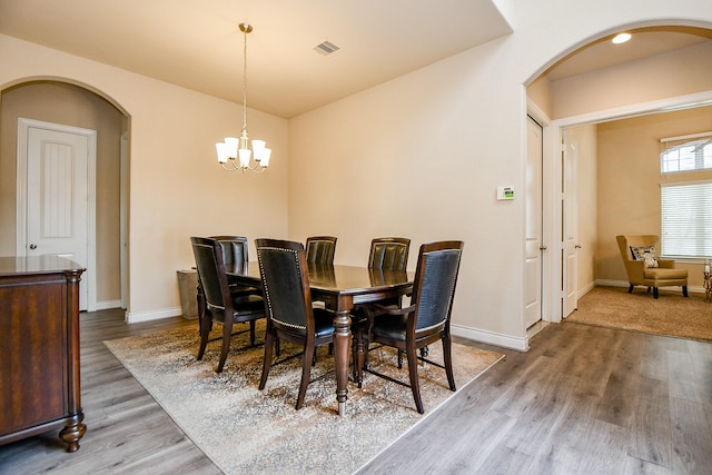 4414 Tilbury Trl, Richmond, TX 77407 - dining area with arched walkways, wood finished floors, a chandelier, and baseboards