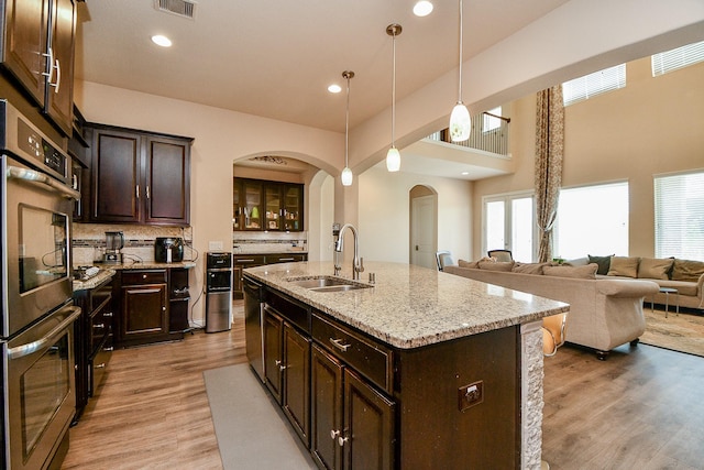 4414 Tilbury Trl, Richmond, TX 77407 - kitchen with a sink, arched walkways, stainless steel double oven, dark brown cabinetry, and recessed lighting