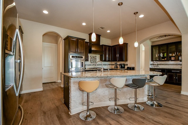 4414 Tilbury Trl, Richmond, TX 77407 - kitchen with stainless steel appliances, arched walkways, tasteful backsplash, dark wood finished floors, and recessed lighting
