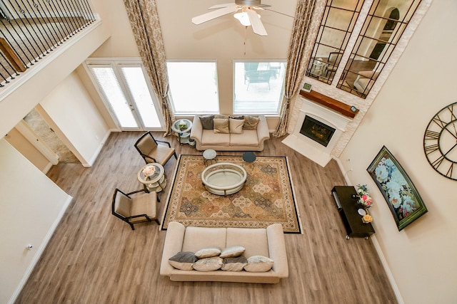4414 Tilbury Trl, Richmond, TX 77407 - living room featuring wood finished floors, a lit fireplace, ceiling fan, baseboards, and a towering ceiling