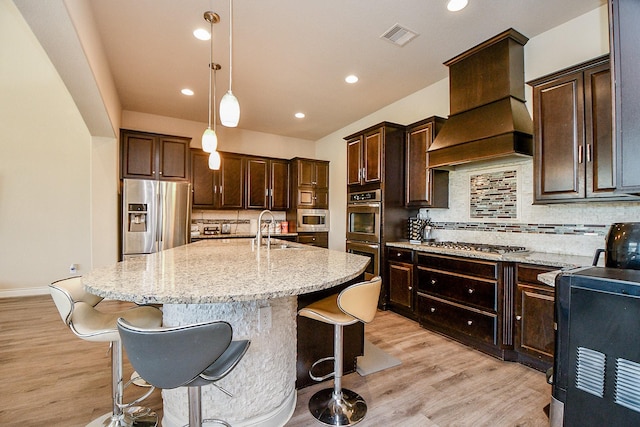 4414 Tilbury Trl, Richmond, TX 77407 - kitchen with appliances with stainless steel finishes, custom exhaust hood, a sink, light stone countertops, and tasteful backsplash