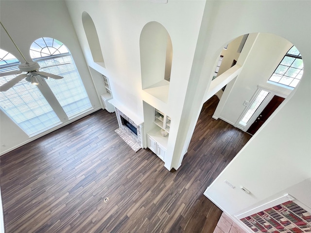 1265 Ridgewood Pl, Houston, TX 77055 - unfurnished living room with a towering ceiling, a ceiling fan, wood finished floors, arched walkways, and built in features