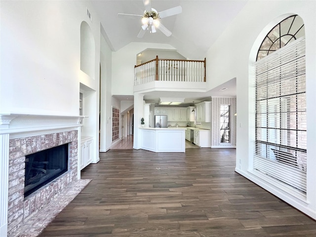 1265 Ridgewood Pl, Houston, TX 77055 - unfurnished living room featuring a ceiling fan, high vaulted ceiling, a tile fireplace, dark wood-type flooring, and built in shelves