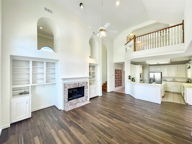 1265 Ridgewood Pl, Houston, TX 77055 - unfurnished living room featuring wood finished floors, a ceiling fan, high vaulted ceiling, a brick fireplace, and built in features