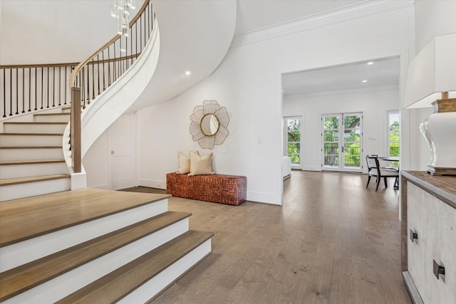 staircase with ornamental molding, wood finished floors, baseboards, and recessed lighting