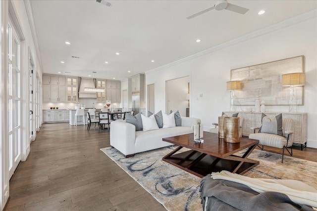 living area with crown molding, wood finished floors, a ceiling fan, and recessed lighting