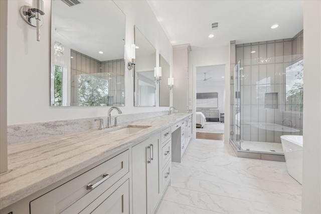 ensuite bathroom with marble finish floors, a shower stall, double vanity, a freestanding tub, and recessed lighting