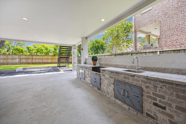 view of patio / terrace featuring stairs, a sink, exterior kitchen, and fence