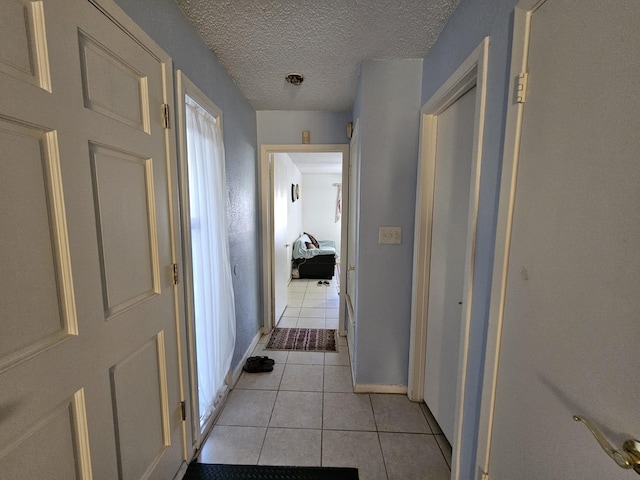 9807 Bent Branch Ln, Dallas, TX 75243 - hallway with light tile patterned floors, a textured ceiling, and baseboards