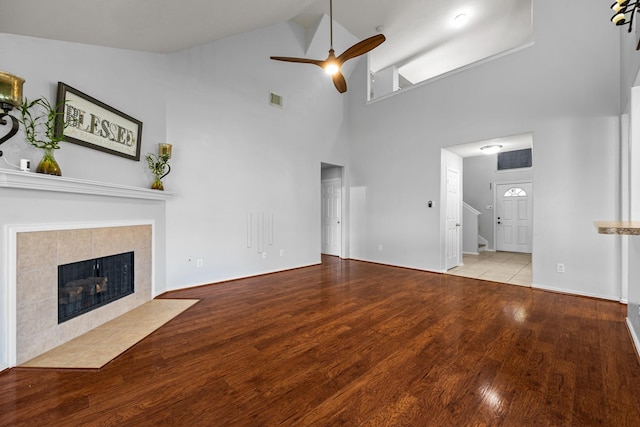 8414 Coriander Ln, Baytown, TX 77521 - unfurnished living room featuring ceiling fan, high vaulted ceiling, a tile fireplace, wood finished floors, and baseboards