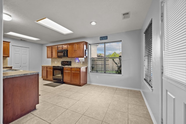 8414 Coriander Ln, Baytown, TX 77521 - kitchen with black appliances, tasteful backsplash, light tile patterned floors, baseboards, and brown cabinetry