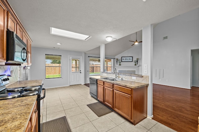 8414 Coriander Ln, Baytown, TX 77521 - kitchen with black appliances, a sink, a skylight, brown cabinets, and light countertops
