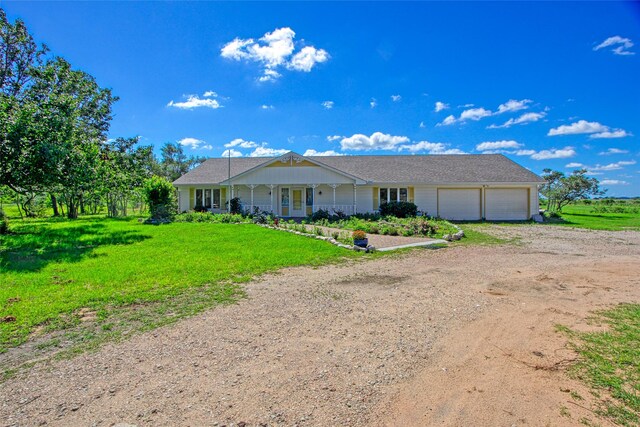 2368 Old Columbus Rd N, Sealy, TX 77474 - ranch-style home featuring dirt driveway, an attached garage, a porch, and a front lawn