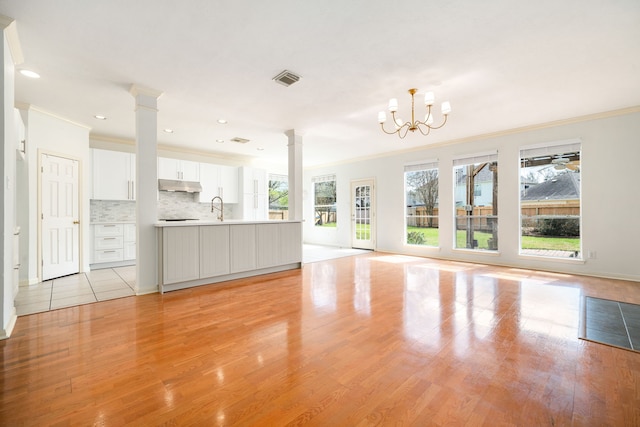 3815 Shadow Knoll Ct, Houston, TX 77082 - unfurnished living room featuring crown molding, ornate columns, light wood-style floors, a sink, and a chandelier