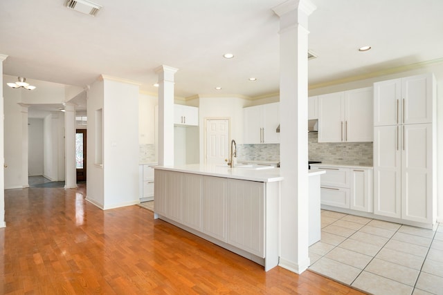 3815 Shadow Knoll Ct, Houston, TX 77082 - kitchen featuring decorative columns, backsplash, light countertops, white cabinets, and ornamental molding