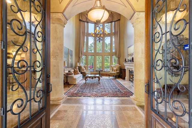 entryway with a chandelier, decorative columns, arched walkways, a high ceiling, and a fireplace