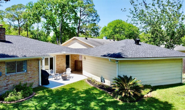 back of property featuring a lawn, roof with shingles, a patio area, and a chimney