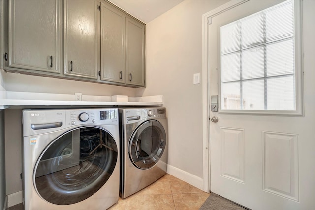 washroom featuring washing machine and dryer, cabinet space, baseboards, and light tile patterned floors