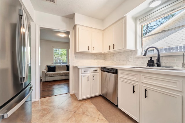 kitchen featuring appliances with stainless steel finishes, light countertops, a sink, backsplash, and a textured ceiling