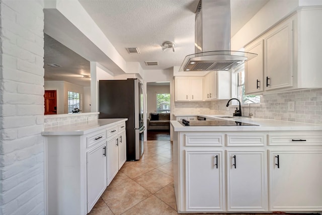 kitchen with island range hood, freestanding refrigerator, a sink, a peninsula, and black electric cooktop