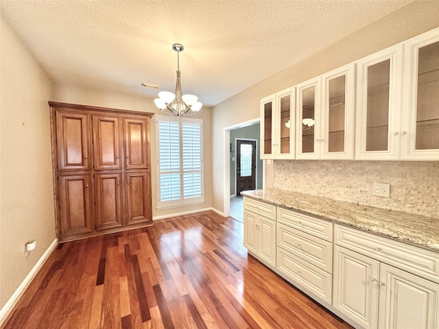 10614 Gold Point Dr, Houston, TX 77064 - kitchen with decorative backsplash, a chandelier, baseboards, light wood-type flooring, and a textured ceiling