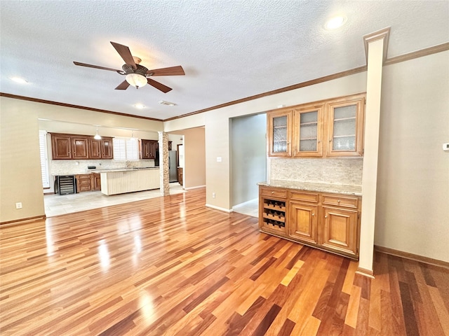 10614 Gold Point Dr, Houston, TX 77064 - unfurnished living room featuring ceiling fan, light wood finished floors, ornate columns, crown molding, and a textured ceiling