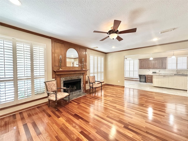 10614 Gold Point Dr, Houston, TX 77064 - living area with crown molding, a tile fireplace, a textured ceiling, light wood-type flooring, and a ceiling fan