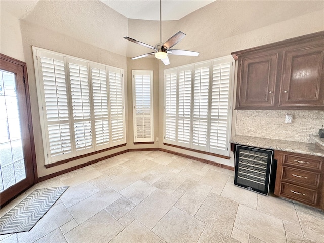 10614 Gold Point Dr, Houston, TX 77064 - unfurnished dining area with wine cooler, ceiling fan, baseboards, and stone tile flooring