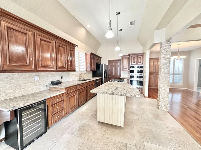 10614 Gold Point Dr, Houston, TX 77064 - kitchen featuring wine cooler, appliances with stainless steel finishes, decorative columns, backsplash, and light stone counters