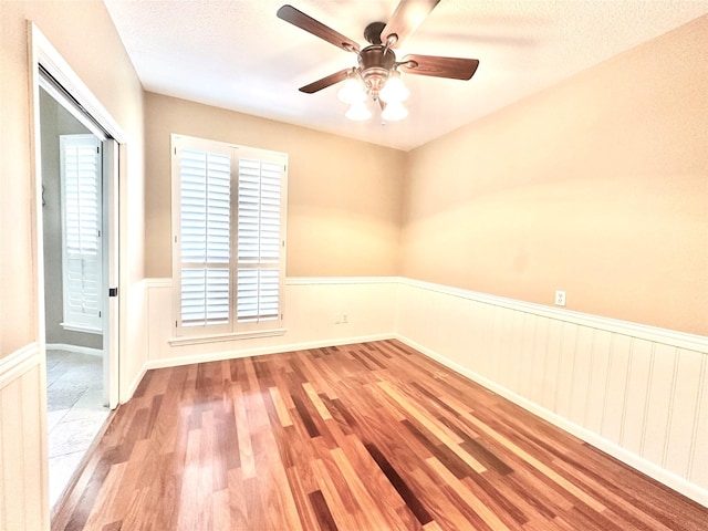 10614 Gold Point Dr, Houston, TX 77064 - spare room featuring wood finished floors, a wainscoted wall, ceiling fan, and a textured ceiling