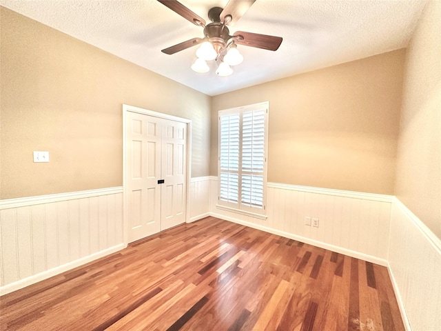 10614 Gold Point Dr, Houston, TX 77064 - spare room featuring wood finished floors, wainscoting, ceiling fan, and a textured ceiling