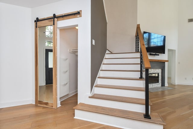 23210 Greenrush Dr, Katy, TX 77494 - staircase featuring wood finished floors, a barn door, baseboards, and a stone fireplace