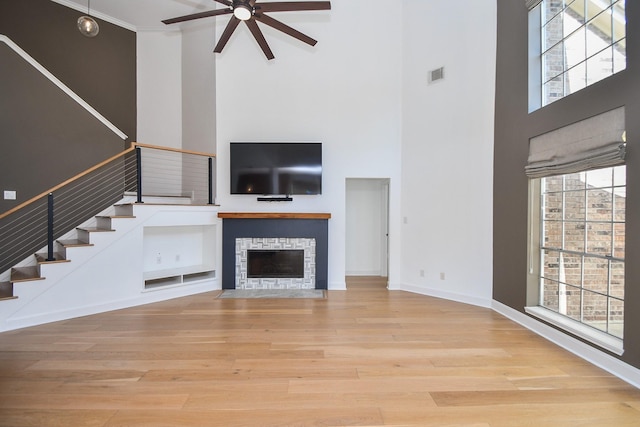 23210 Greenrush Dr, Katy, TX 77494 - unfurnished living room featuring a high ceiling, a ceiling fan, stairway, wood finished floors, and a stone fireplace