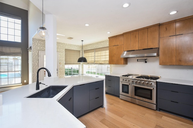 23210 Greenrush Dr, Katy, TX 77494 - kitchen featuring range with two ovens, under cabinet range hood, a sink, modern cabinets, and decorative light fixtures