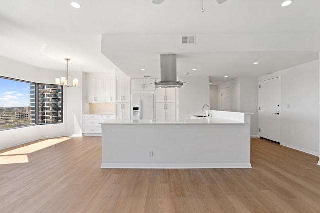 2001 Holcombe Blvd Unit 1605, Houston, TX 77030 - kitchen featuring island range hood, white refrigerator with ice dispenser, white cabinetry, light wood-style flooring, and baseboards