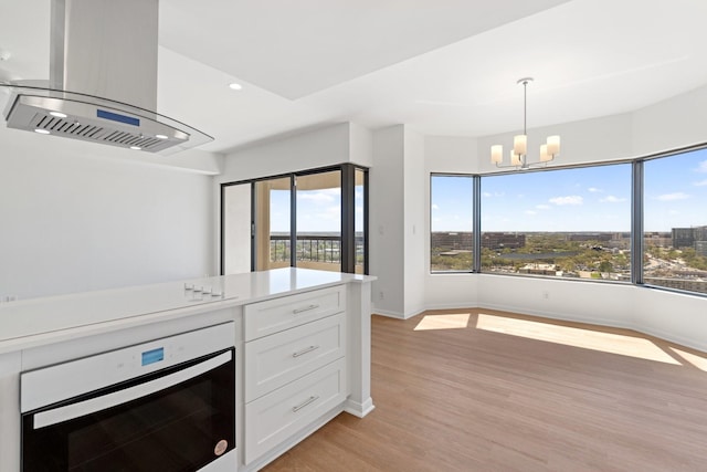 2001 Holcombe Blvd Unit 1605, Houston, TX 77030 - kitchen featuring island exhaust hood, a chandelier, white cabinetry, light wood-style flooring, and recessed lighting