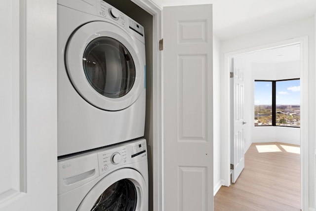 2001 Holcombe Blvd Unit 1605, Houston, TX 77030 - clothes washing area featuring stacked washing machine and dryer, light wood finished floors, and baseboards