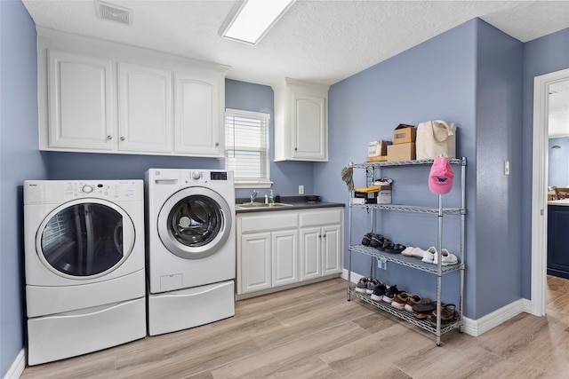 1815 Tiki Dr, Tiki Island, TX 77554 - clothes washing area featuring cabinet space, washing machine and clothes dryer, light wood-style floors, and baseboards